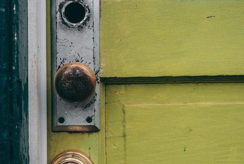 brown door knob in green wooden door