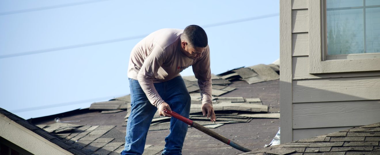 a man with a hammer on top of a roof