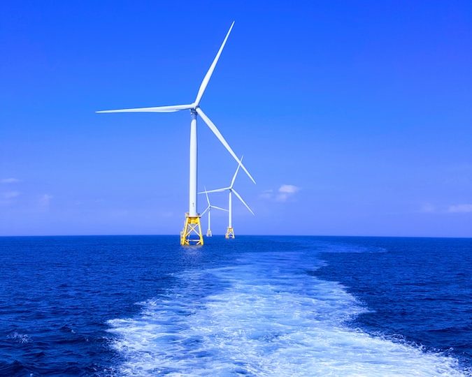 three white wind turbine on sea