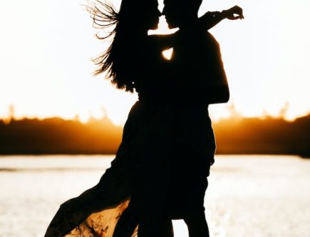 silhouette of woman standing on beach during sunset