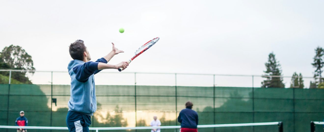 four men playing double tennis during daytime