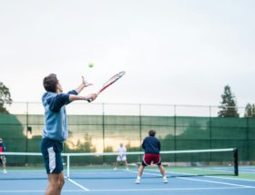 four men playing double tennis during daytime