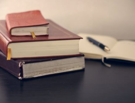 selective focus photography of three books beside opened notebook