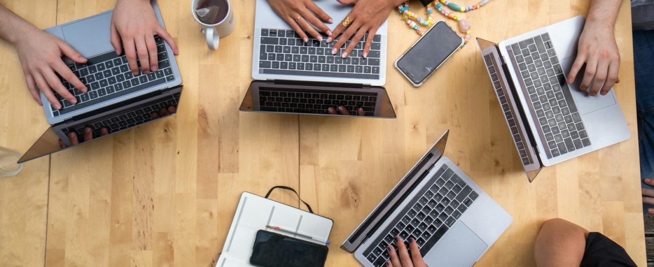 person using macbook pro on brown wooden table