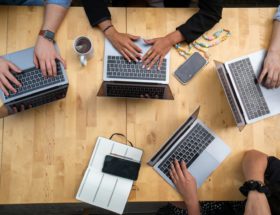 person using macbook pro on brown wooden table